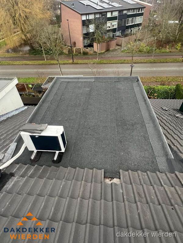 Plat dak inspectie met bitumen bedekking naast schuin pannendak in Wierden