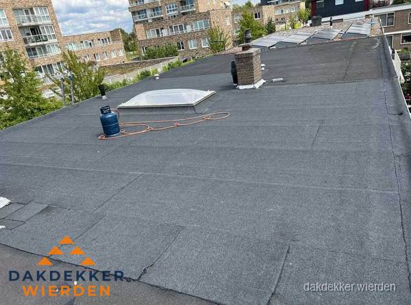 Bitumen dakbedekking op plat dak met lichtkoepel en schoorsteen in Wierden