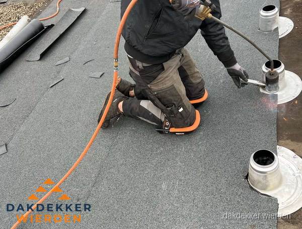 Dakdekker repareert bitumen dakleer bij dakdoorvoer in Wierden