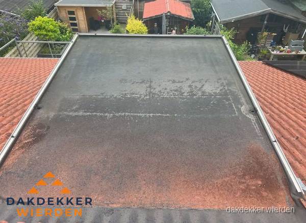Verouderd plat dak met slijtage tussen schuine daken in Wierden Verouderd plat dak met slijtage tussen schuine daken in Wierden