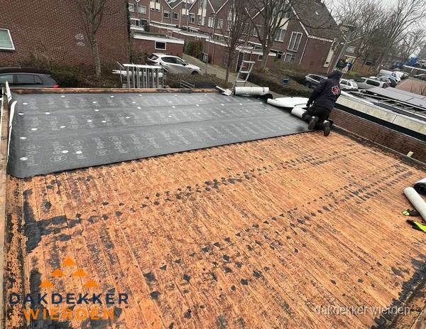 Dakdekker legt onderlaag op plat dak met houten constructie in Wierden